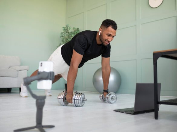 Man performing strength training exercise during home workout routine with dumbbells and virtual training