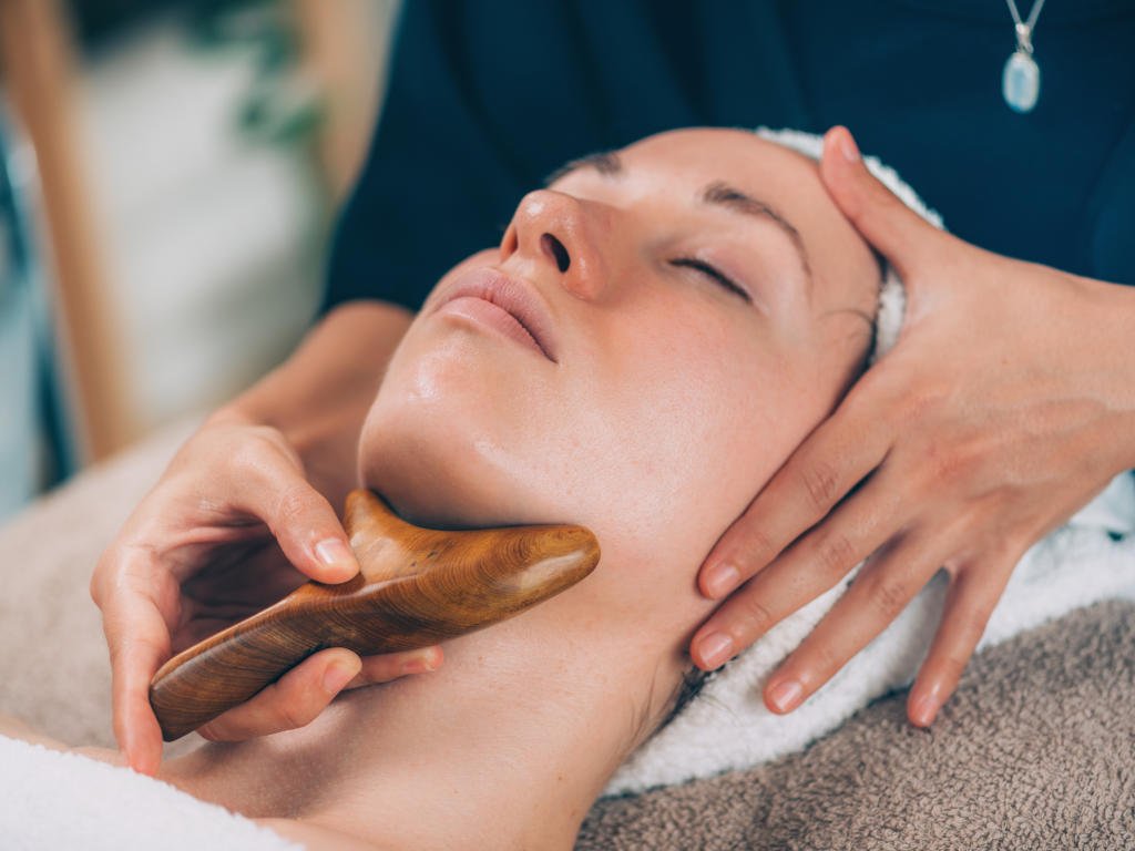 Woman performing facial massage as part of self-care for wellness and beauty