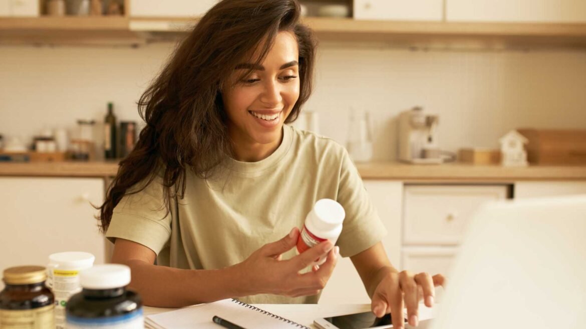 Woman researching vitamin D supplements at home kitchen table with multiple supplement bottles