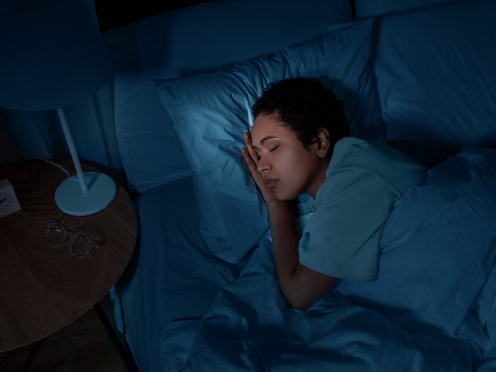 Woman peacefully sleeping at night as part of consistent sleep schedule and daily health habits