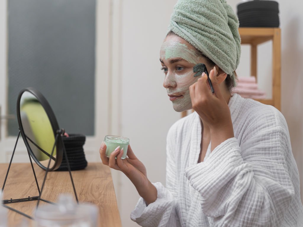 Woman applying a homemade face mask using DIY hydration techniques in front of a mirror