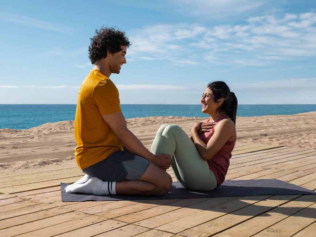 Young adults practicing emotional wellness with outdoor exercise on the beach