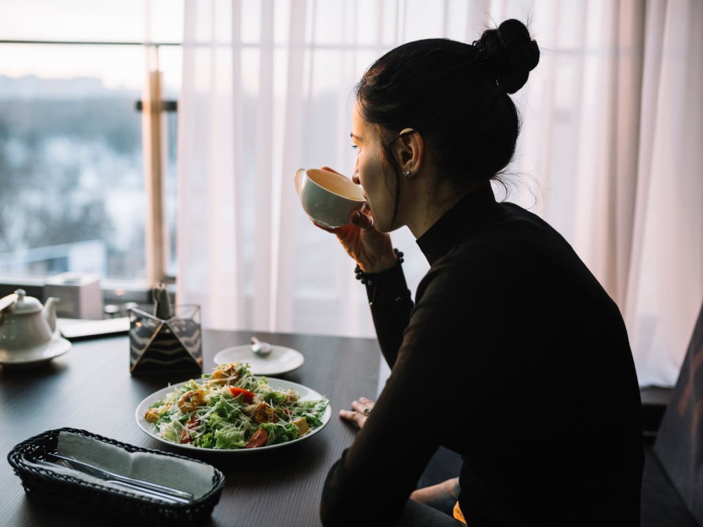 Woman demonstrating healthy eating habits with mindful tea drinking and fresh salad in peaceful setting