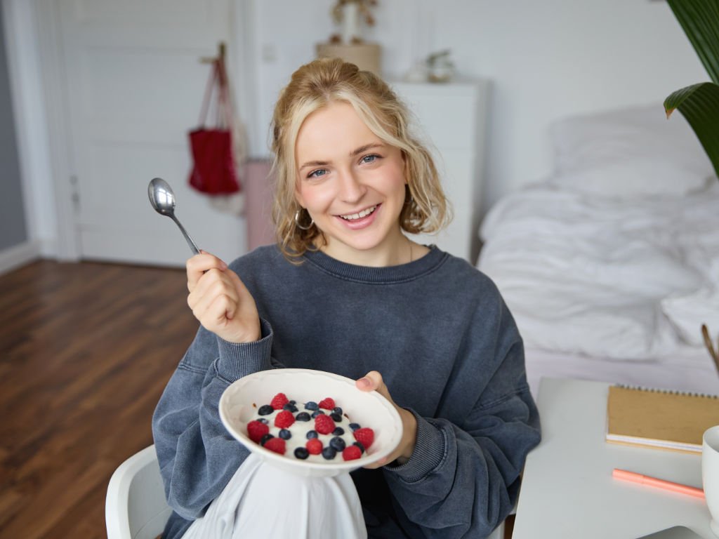 Woman enjoying probiotic foods yogurt with berries for healthy morning breakfast routine to support gut health
