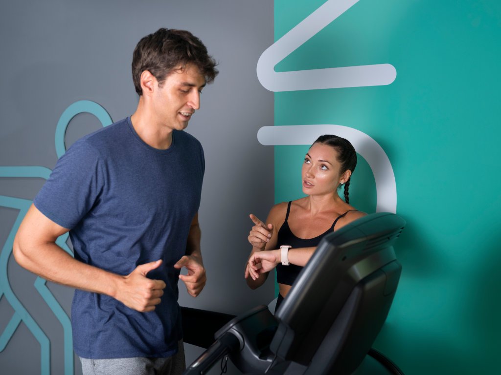 Fitness trainer helping man overcome cardio workouts challenges on treadmill