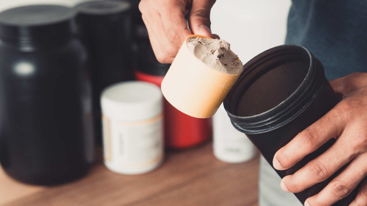 Person scooping pre-workout supplements powder before workout for energy and performance