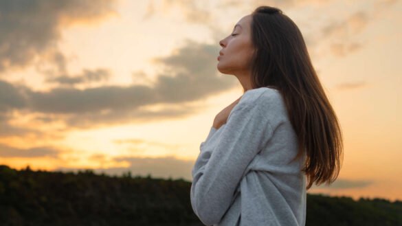 Side view of a woman reflecting at sunset, embodying emotional wellness and inner peace in nature