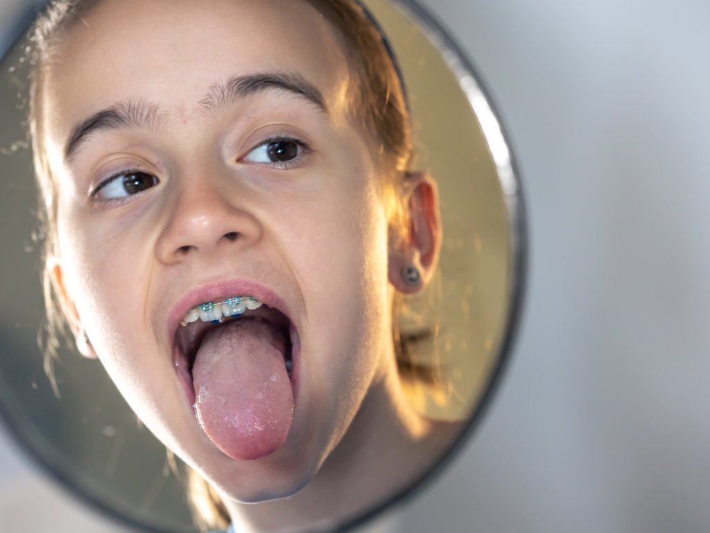 Person examining tongue coating, a sign of poor gut health and potential bad breath