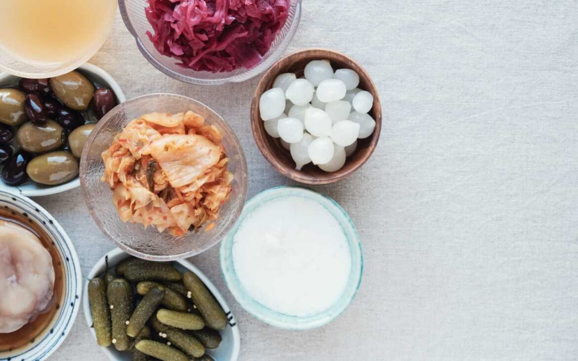 Variety of probiotic foods including kimchi, pickles, kefir grains, yogurt and fermented vegetables arranged overhead for gut health benefits
