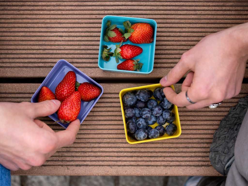Fresh berry superfood selection in colorful containers showing blueberries and strawberries for brain health