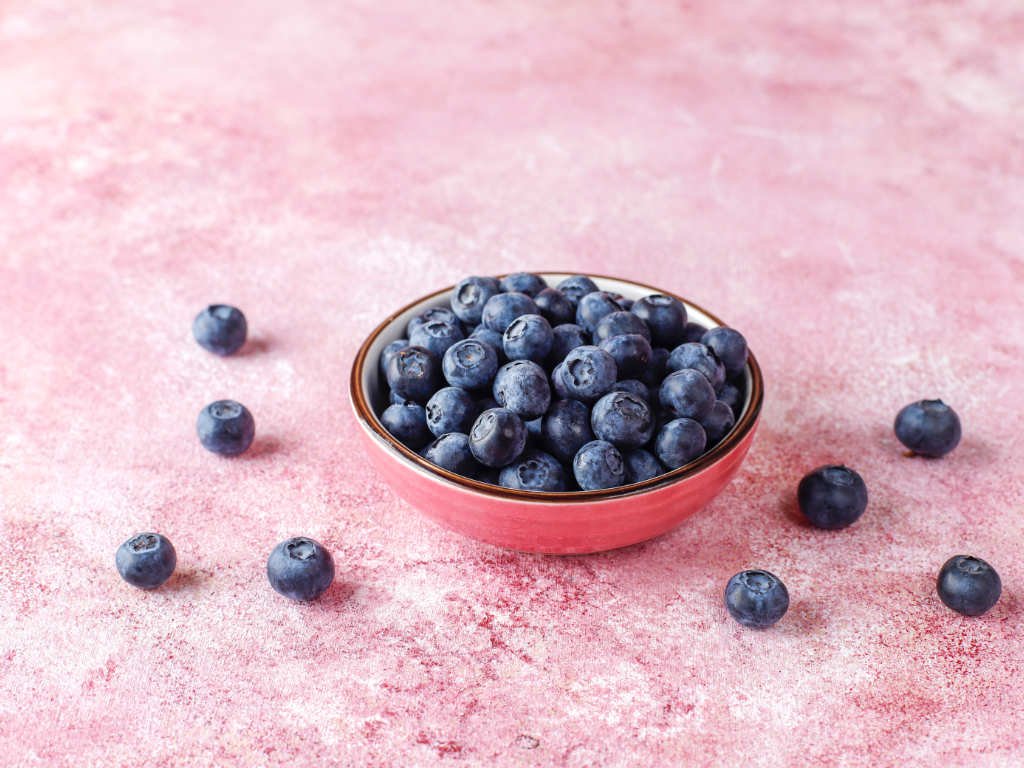 Fresh blueberries superfood for brain health in coral bowl on pink background promoting mental clarity and cognitive function