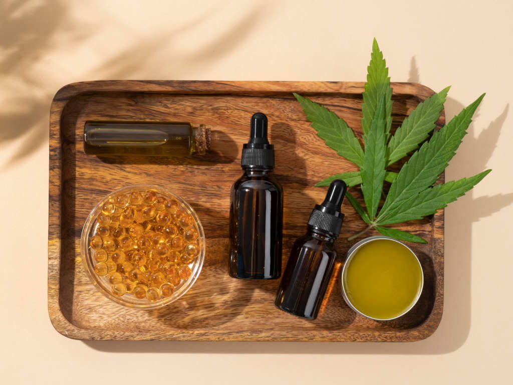 Various CBD oils for stress management including tinctures, capsules, gel, and lotion products displayed on wooden tray