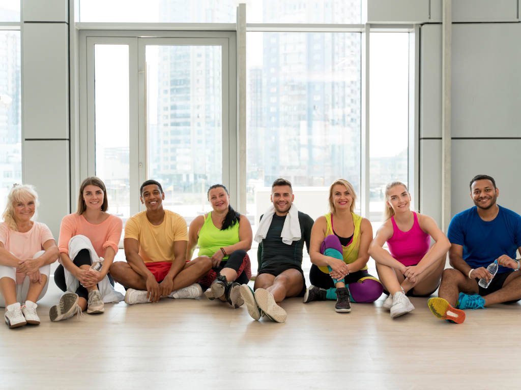 Fitness trends 2025 showcasing inclusivity with diverse group of people of different ages, ethnicities and body types sitting together after workout class