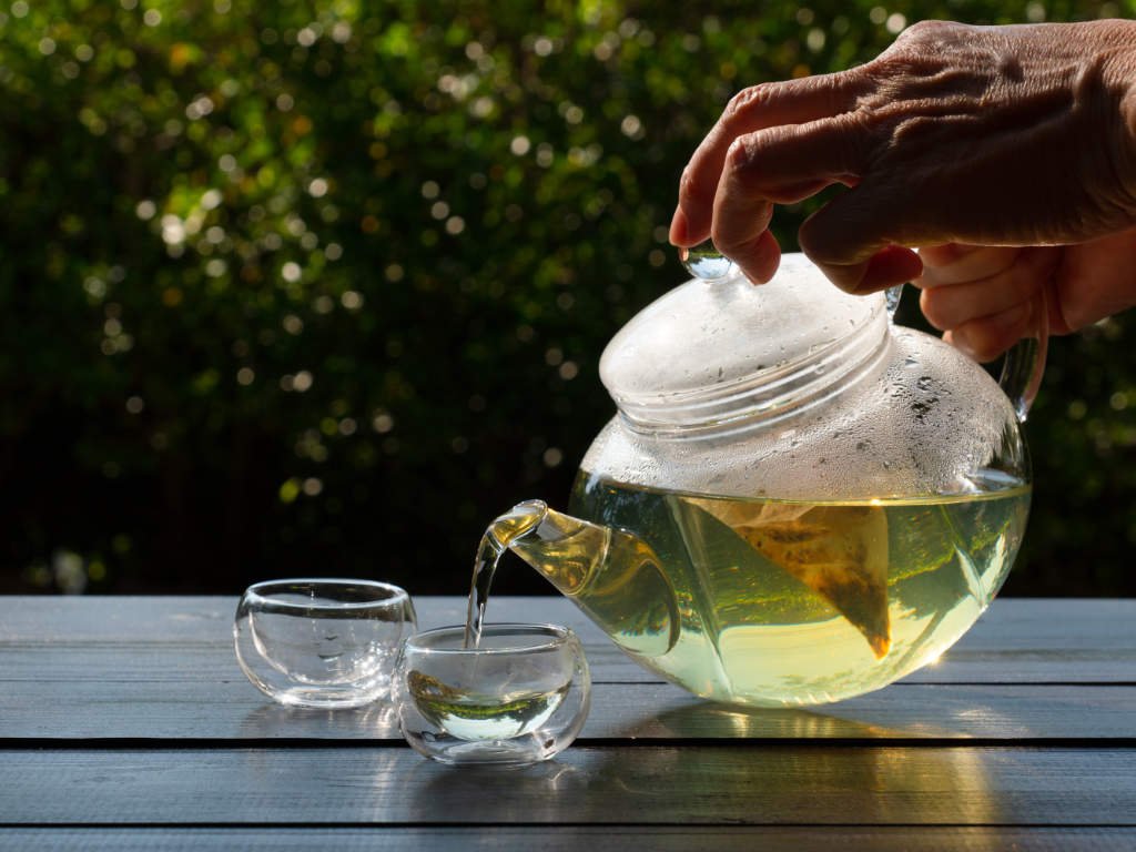 Green tea superfood being poured from glass teapot into cup for brain health and mental clarity enhancement