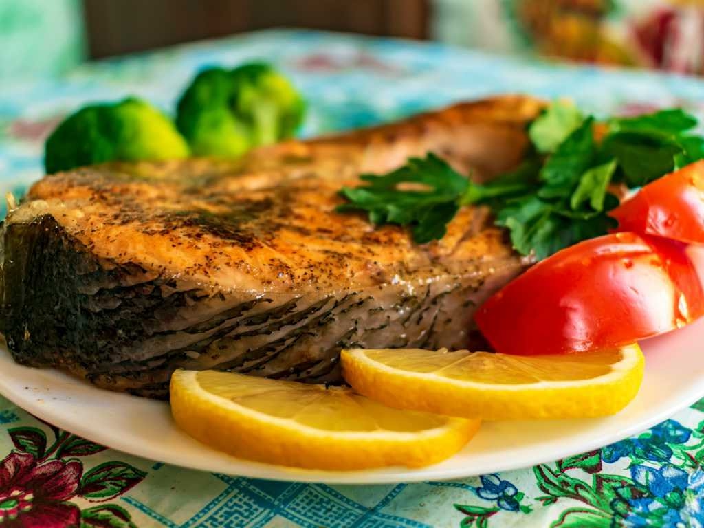Overcoming anxiety with grilled fish rich in omega-3 fatty acids, served with fresh vegetables, tomatoes and lemon for optimal mental wellness