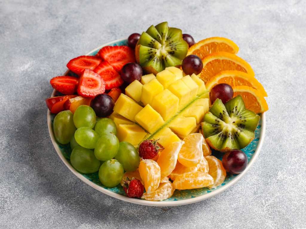 Colorful mixed fruit platter with strawberries, kiwi, pineapple and grapes - natural foods that boost weight loss with vitamins and fiber