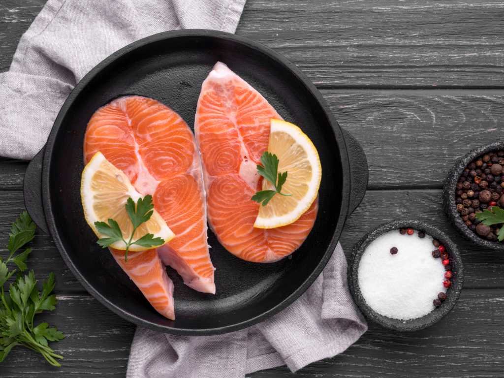 Premium salmon steaks with lemon and herbs showcasing omega-3 benefits from fatty fish as the gold standard source for heart health