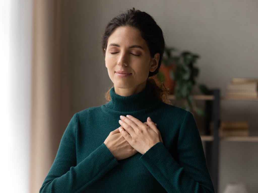 Woman practicing 4-7-8 breathing technique for overcoming anxiety - peaceful meditation with hands on heart