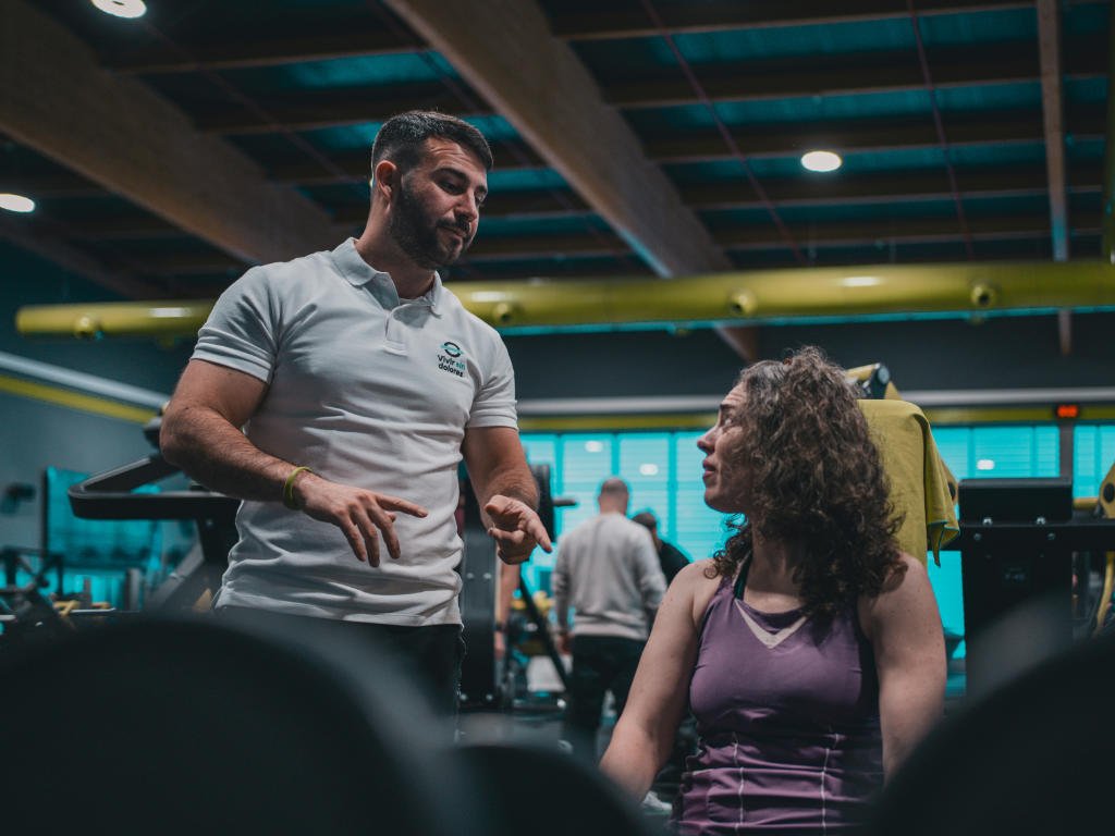 Fitness trainer providing personalized post-workout recovery guidance to client in gym, emphasizing individual needs assessment