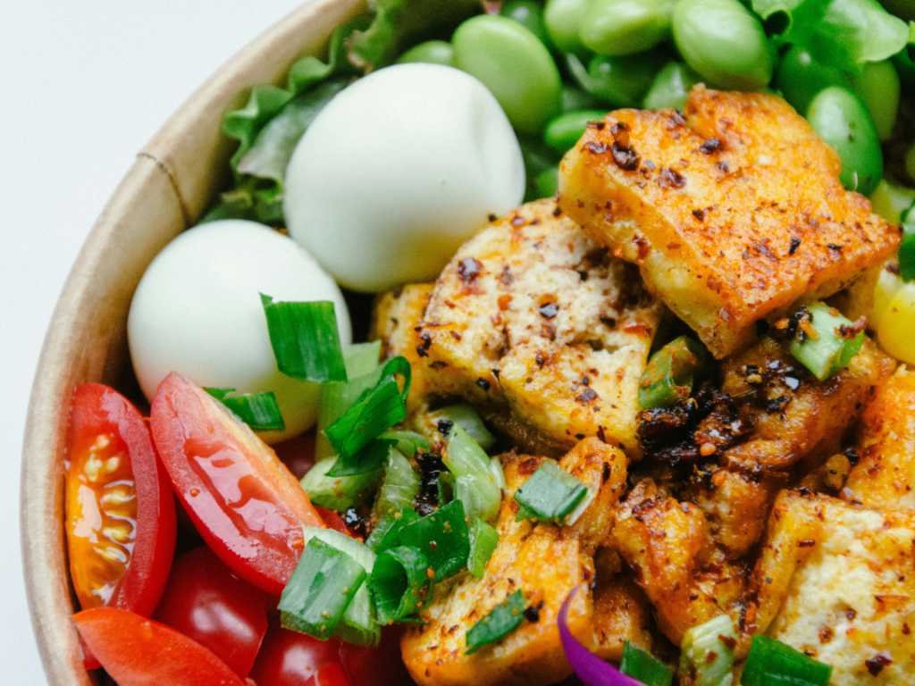 Nutritious post-workout recovery meal featuring protein-rich tofu, hard-boiled eggs, fresh vegetables and grains in a colorful bowl
