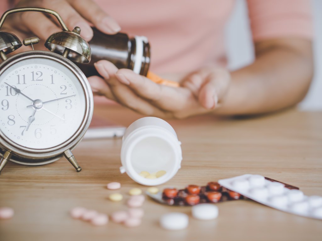 Alarm clock and supplements on bedside table showing optimal timing for taking prebiotic supplements for maximum gut health effectiveness