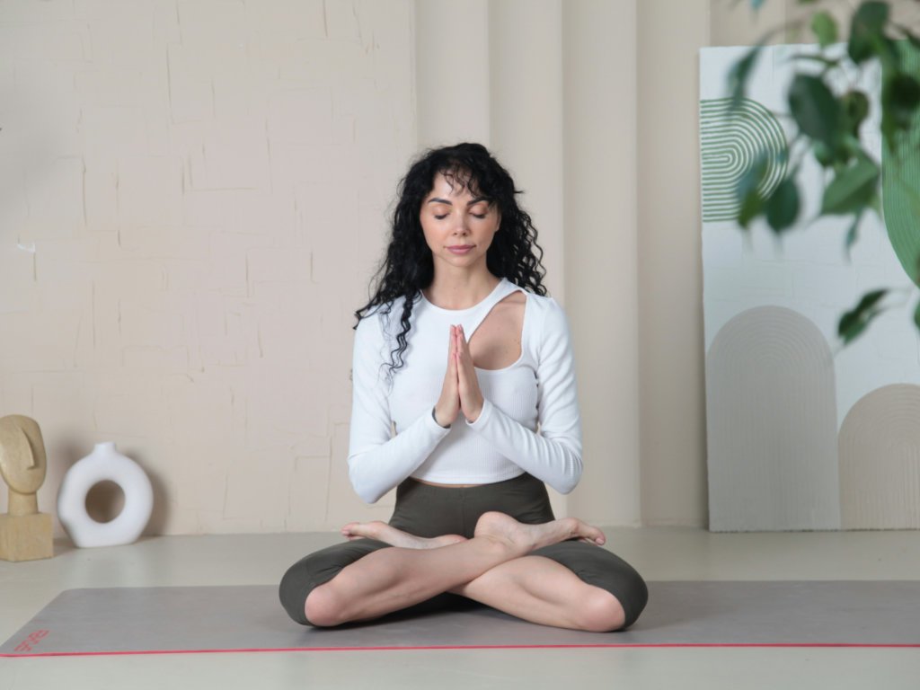 Woman in lotus position demonstrating mindful meditation benefits in modern wellness space for stress relief and mental health