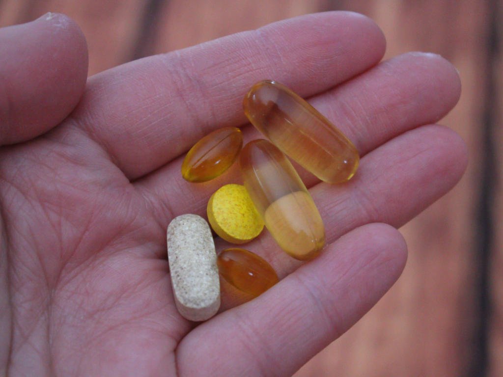 Person holding various Vitamin B12 supplements and vitamins in palm considering supplementation options for health