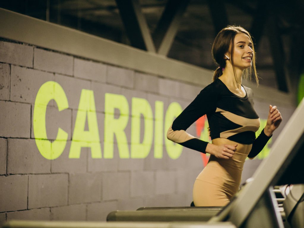 Woman performing cardiovascular exercises for women's fitness on treadmill in modern gym with cardio equipment and motivational branding