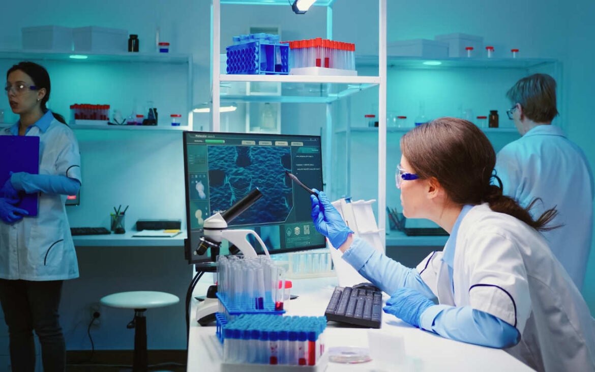 Modern health diagnostics laboratory with researchers using advanced computer technology and analytical equipment for medical testing
