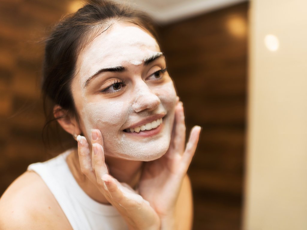 Young woman exfoliating her face as part of her anti-aging skincare routine for glowing skin