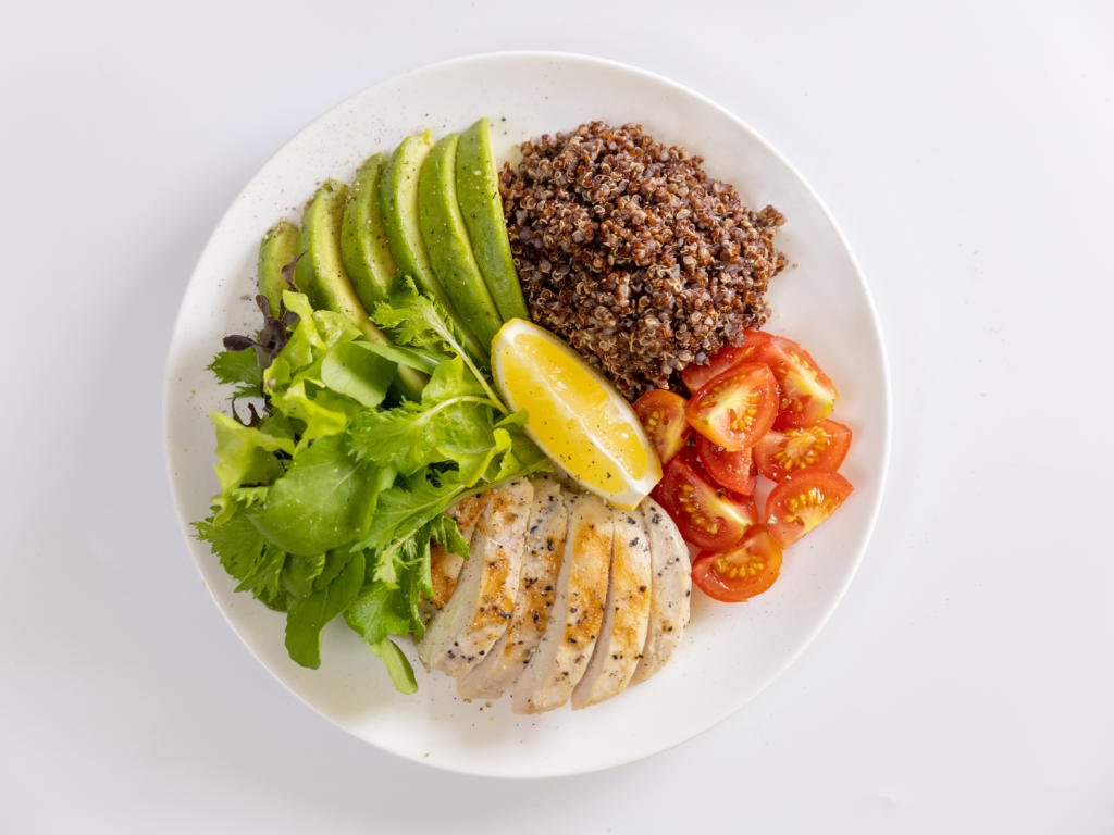 Balanced nutrition meal bowl with grilled chicken, quinoa, avocado and vegetables for optimal balanced nutrition