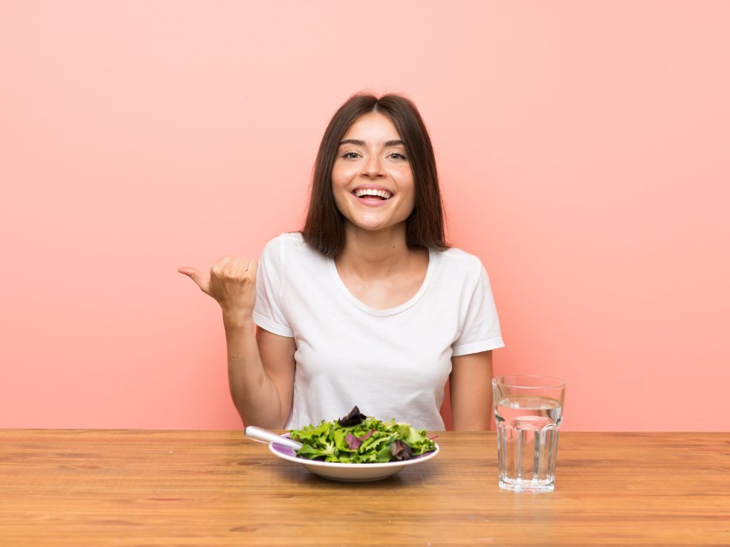 Happy woman giving thumbs up with healthy salad demonstrating successful hormonal balance tips through strategic dietary changes