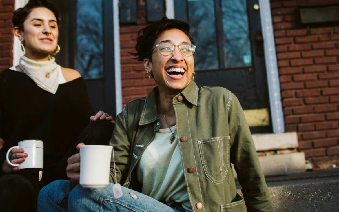 Two friends laughing together over coffee demonstrating effective ways to combat stress through social connection and joyful moments