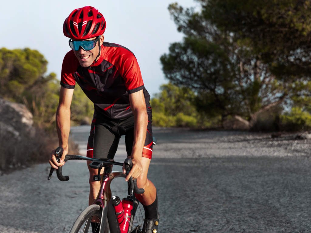 Cyclist performing high-intensity cardio exercises on road bike in aerodynamic position for power and endurance training