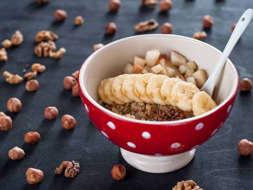 Energizing superfoods for women featuring breakfast bowl with sliced banana, mixed nuts, seeds and grains for sustained power