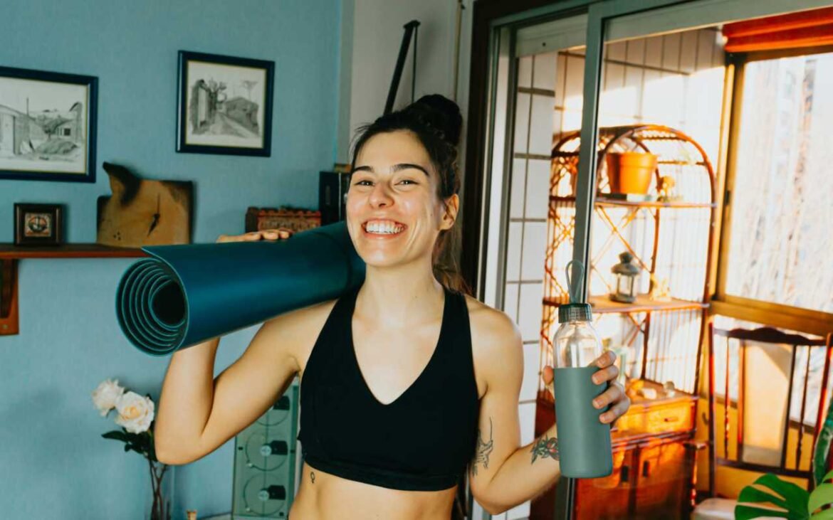 Woman smiling with yoga mat and water bottle representing healthy lifestyle and hormonal balance tips