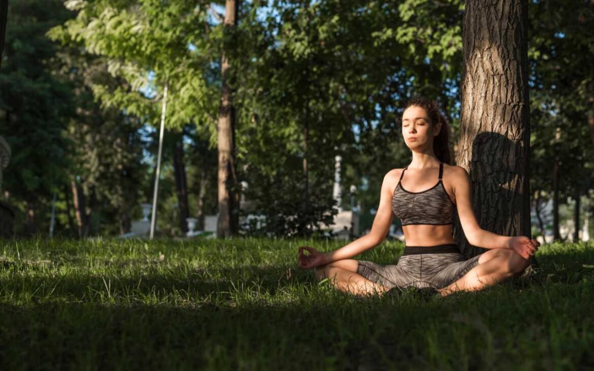 Woman practicing meditation mental health strategies in peaceful park setting under tree for natural wellness