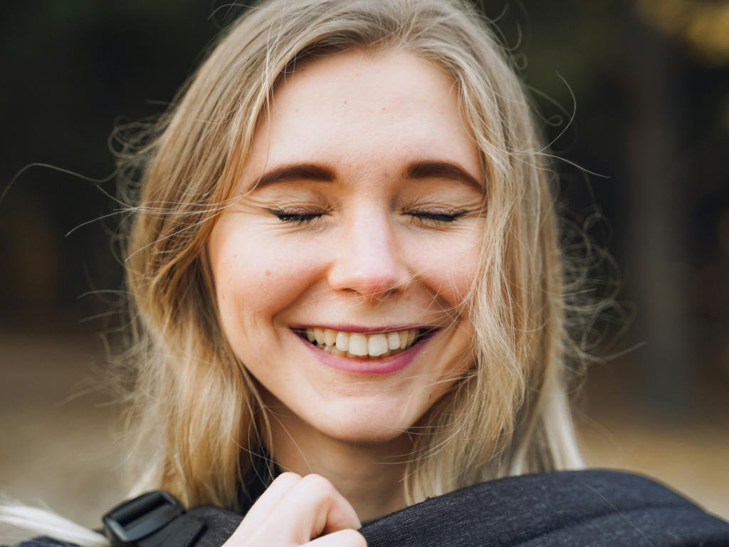 Happy woman smiling outdoors demonstrating improved mental health and mood benefits from probiotics supplements through gut-brain connection