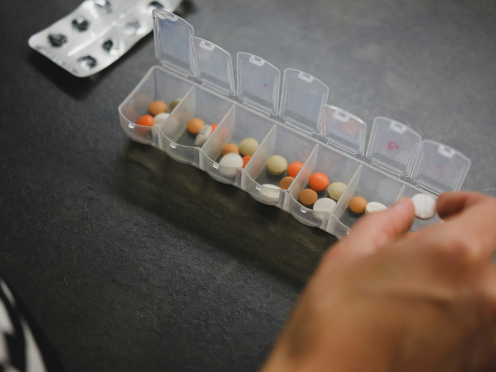 Weekly pill organizer filled with various probiotics supplements showing daily dosing routine for beginners starting their probiotic journey
