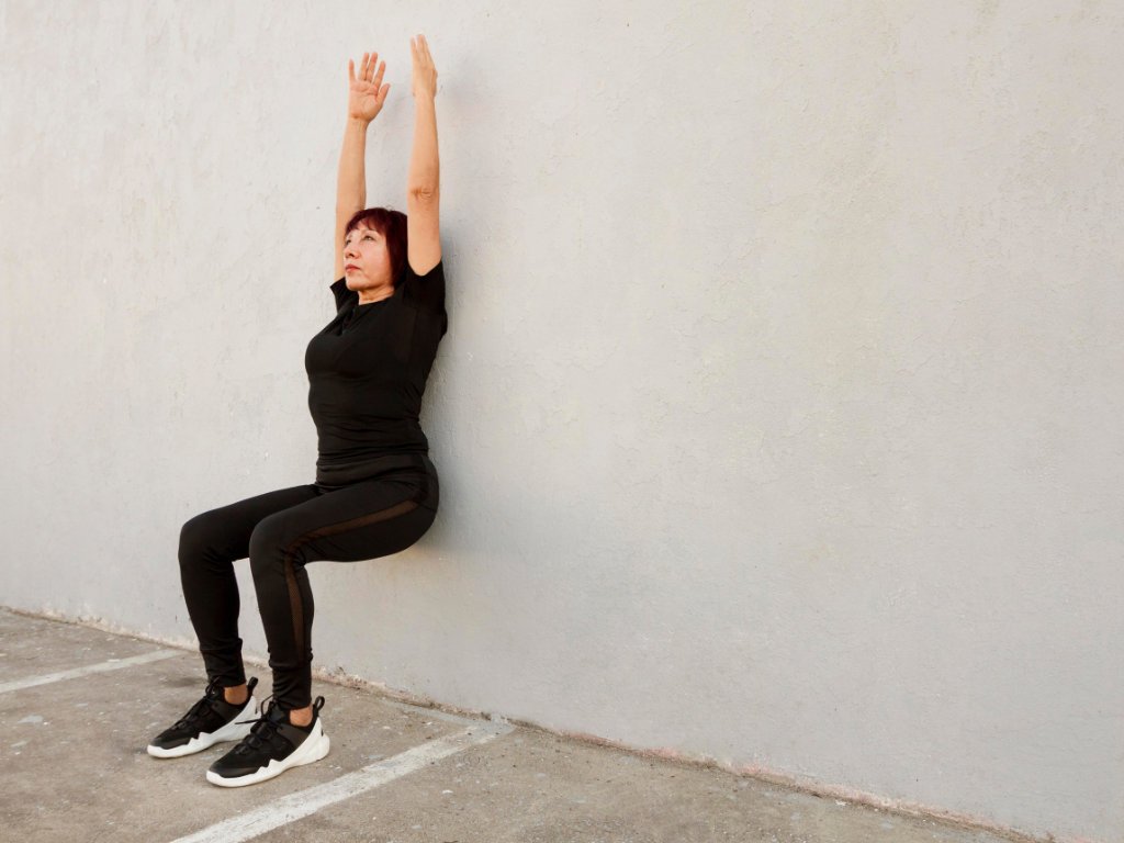 Professional woman demonstrating ultimate fitness wall squat exercise in 7-minute scientific workout routine
