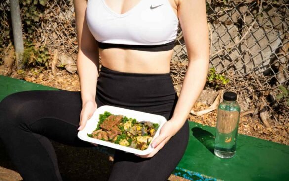 Woman in workout attire holding nutritious salad bowl showing how to align diet with fitness goals for optimal results