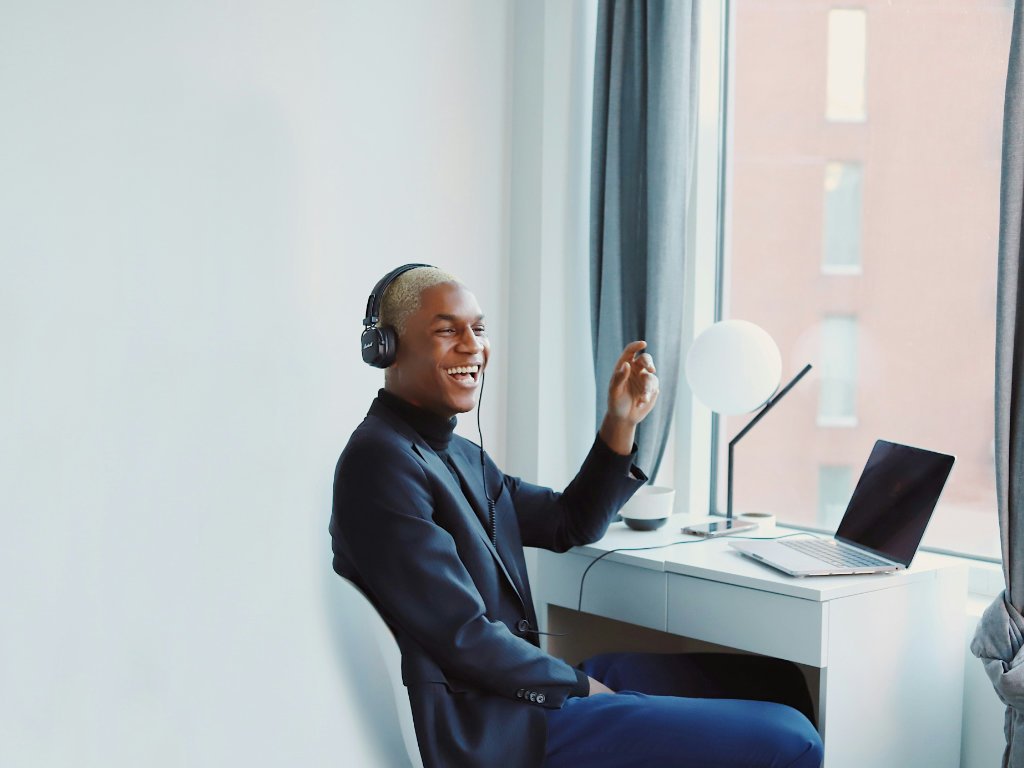 Happy professional laughing during video conference showing positive emotional wellness at work in modern office environment