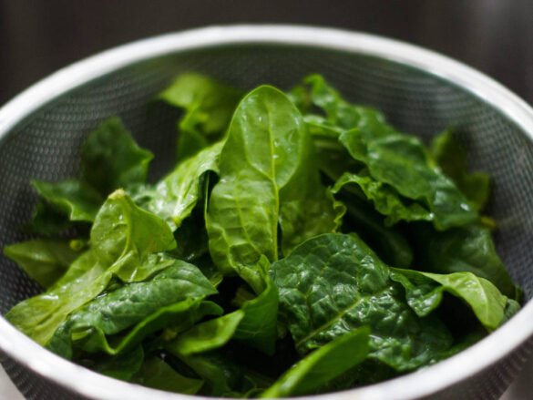 Fresh spinach leaves in colander showcasing leafy green superfoods for daily nutrition optimization