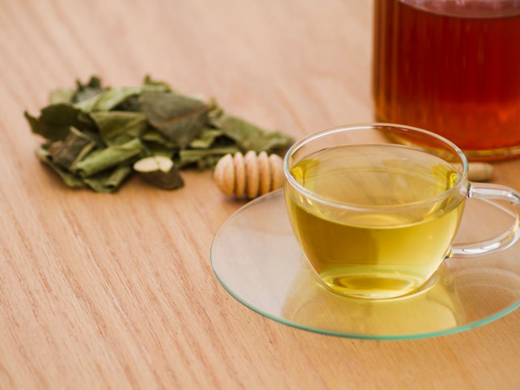 Glass cup of golden herbal teas for focus with dried herbs and honey for ginkgo biloba memory enhancement