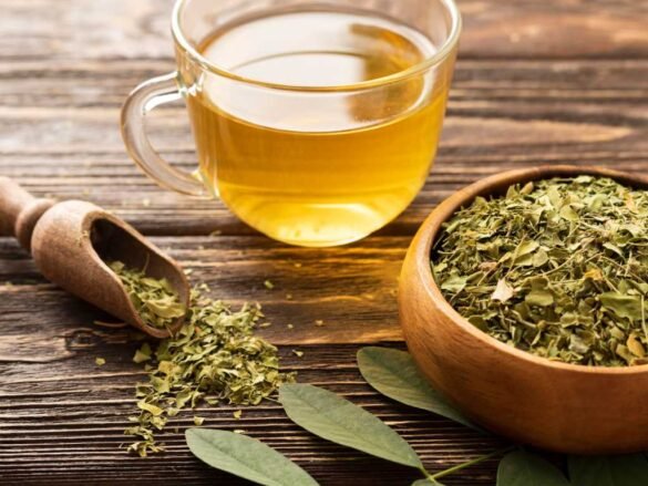 Natural appetite suppressants herbal tea in glass mug with dried herbs for weight loss, showing plant-based appetite control remedies on wooden table