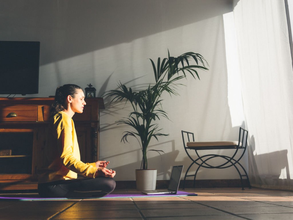 Woman practicing meditation at home to overcome time constraints while implementing long-term health strategies for busy lifestyle