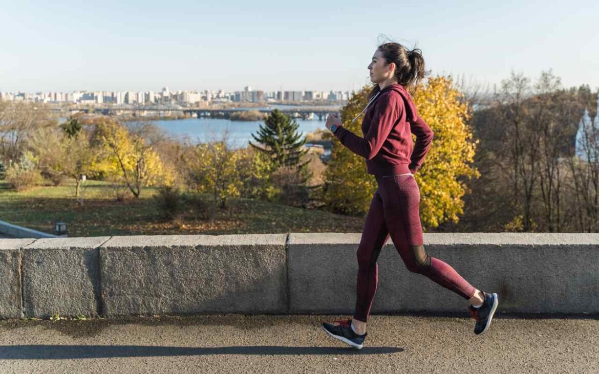 Woman implementing long-term health strategies through outdoor running exercise along scenic waterfront path