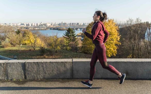 Woman implementing long-term health strategies through outdoor running exercise along scenic waterfront path