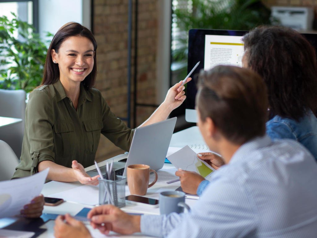 Happy female employee smiling during collaborative team meeting demonstrating effective mental health support and emotional wellness at work