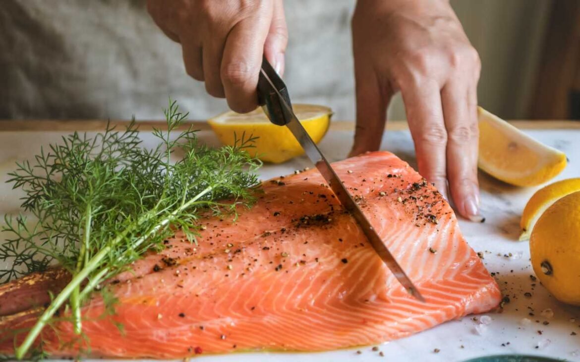 Person cutting fresh salmon with natural remedies including herbs and lemon for effective fat loss and healthy weight management
